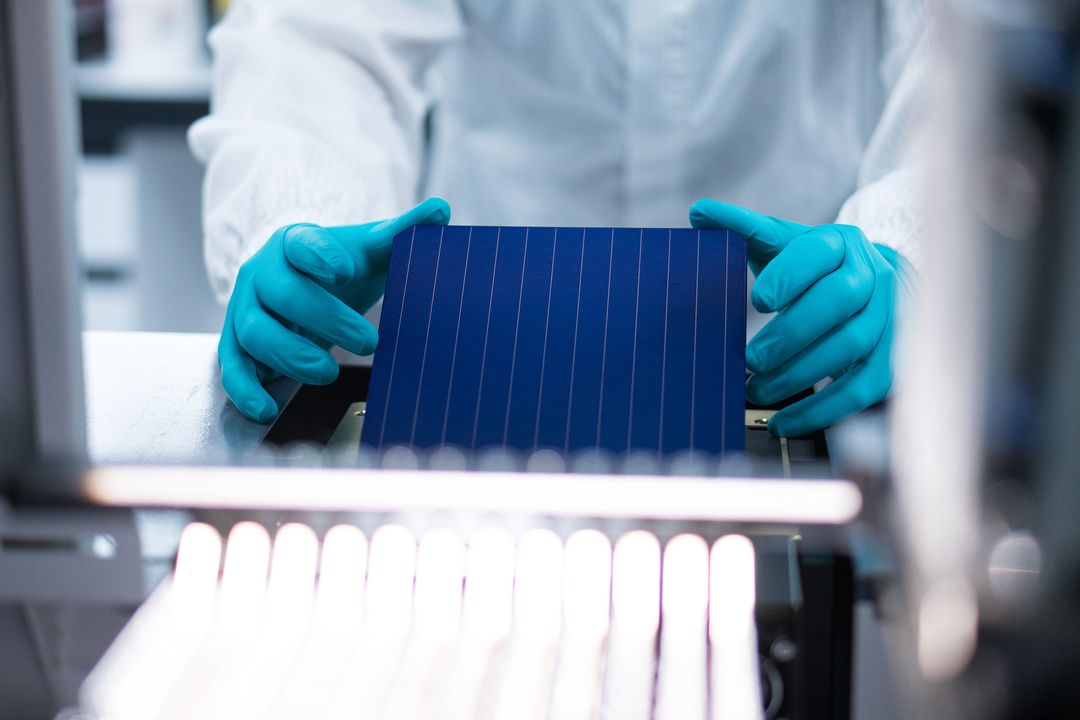 Rectangular solar cell held between gloved hands 