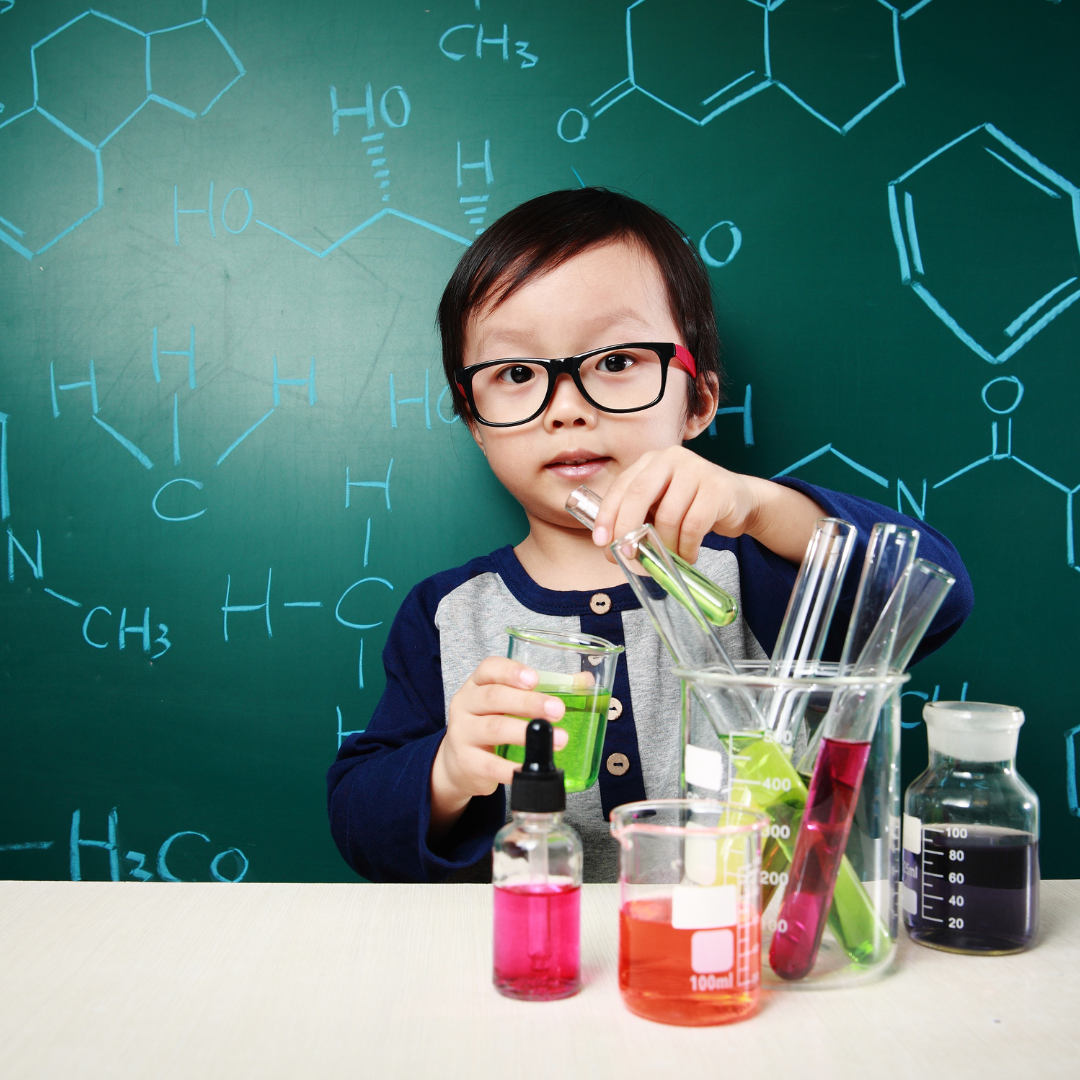 Child with a chemistry set, standing in front of a blackboard full of chemical structures 