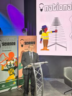 Prof Tony Haymet appears in front of a National Science Week banner, standing at a lectern. 