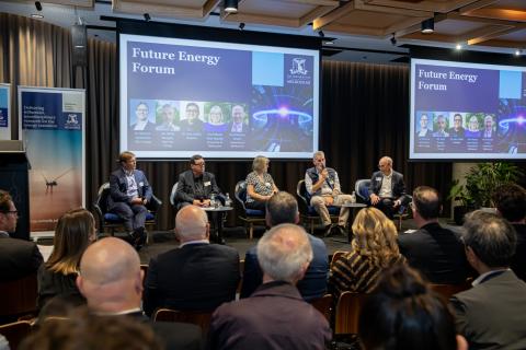 Audience in foreground watching presentation slides on a screen in the background at the Future Energy Forum. 