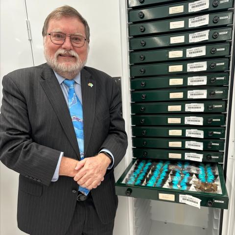 Image of Prof Tony Haymet standing in front of collection of butterfly samples