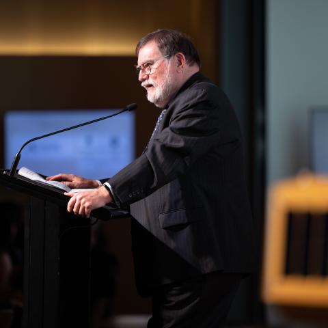 Side view of Prof Tony Haymet standing at lectern speaking into a microphone