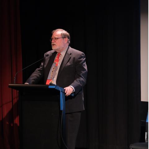 Prof Tony Haymet speaking into a microphone in front of a lectern.