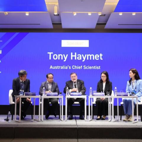 An image of a group of 5 people seated on stage. In front of a screen with the words: Tony Haymet Australia's Chief Scientist