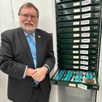 Image of Prof Tony Haymet standing in front of collection of butterfly samples